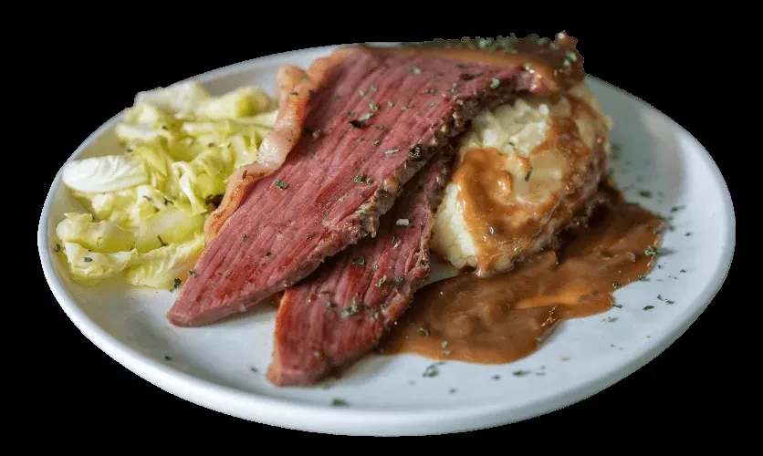 Close-up of plated roast beef, mashed potatoes with gravy, and cabbage.