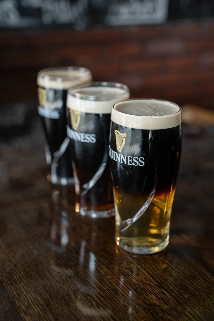 Three layered Guinness stout and lager on dark wood.