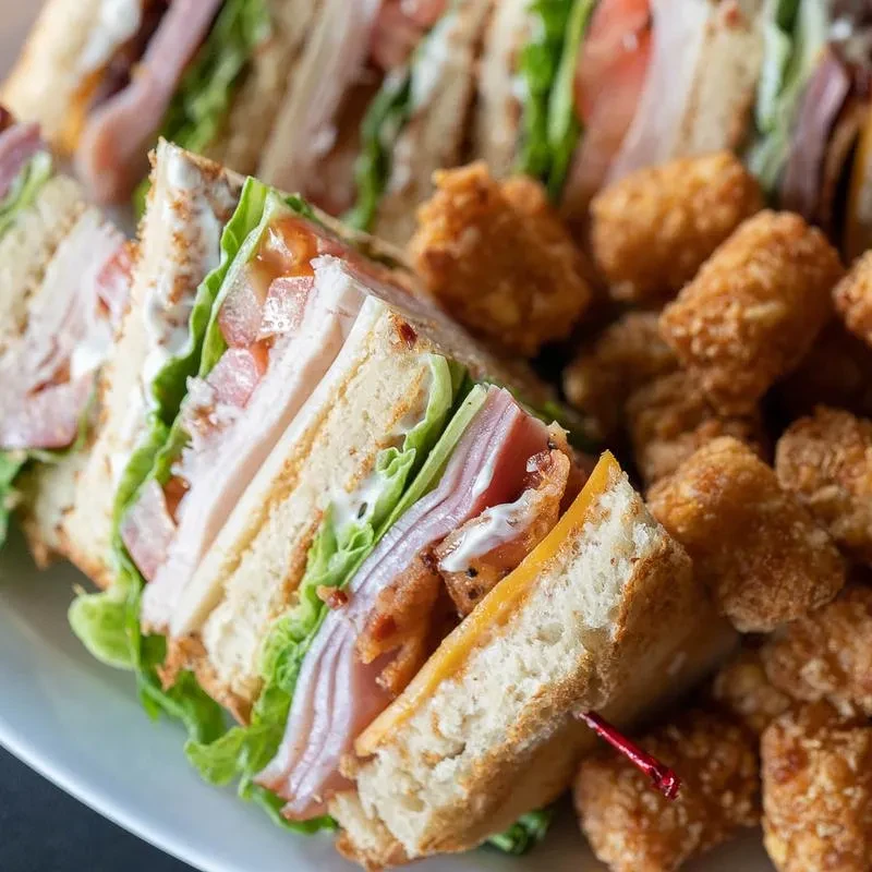Club sandwiches, showing layers, with golden potato nuggets.