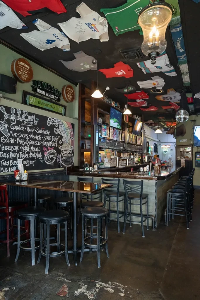 Empty sports bar with long counter, hanging jerseys, and chalkboard.
