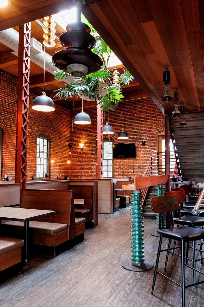 Empty rustic industrial restaurant with exposed brick and diverse seating.