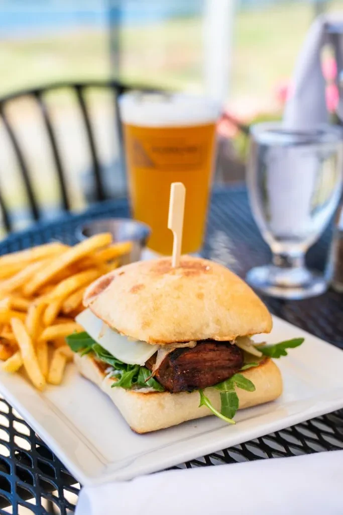 Square grilled ciabatta sandwich with fries served outdoors.