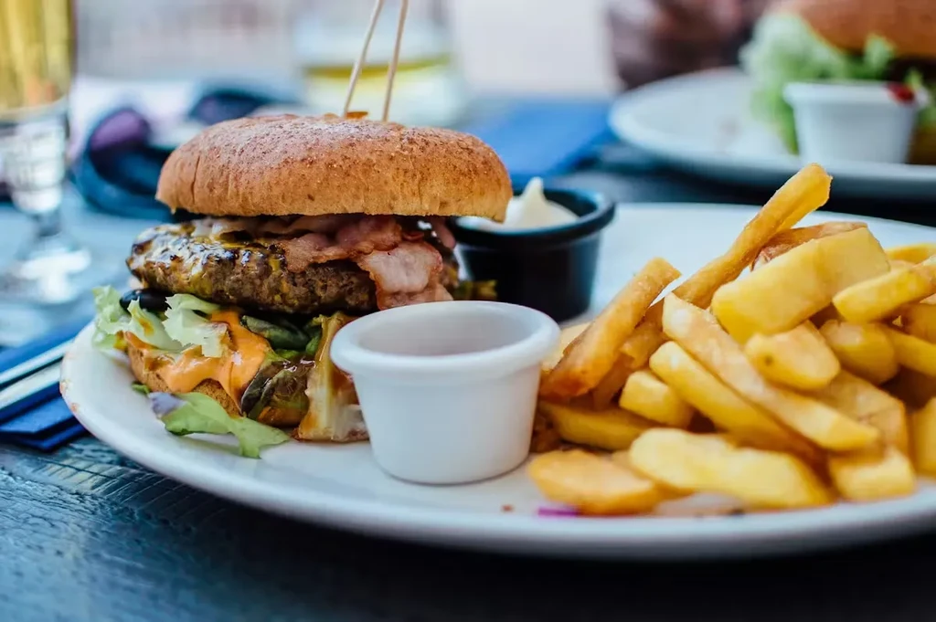 Gourmet burger, golden fries, and two dipping sauces on a rustic plate.