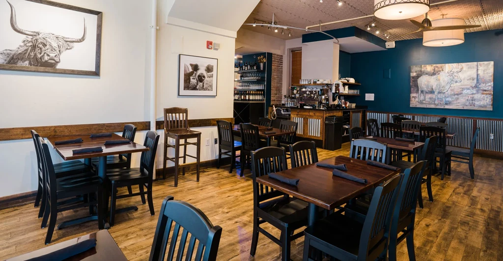 Modern rustic restaurant interior with animal art, dark wood, teal wall.