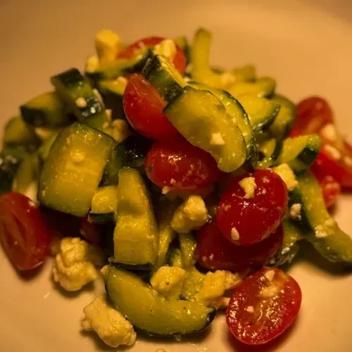 Fresh salad with cucumber, cherry tomatoes, and crumbled feta cheese.