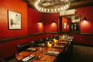 Red private dining room with long table, candles, chandelier, and mirror.