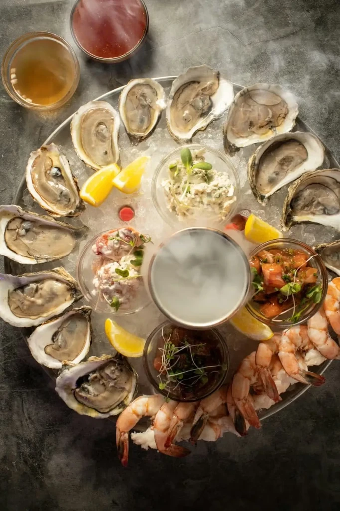 Overhead: Seafood platter with oysters, shrimp, sauces, and dry ice mist.