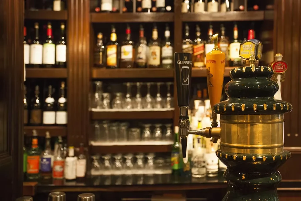 Well-stocked bar with beer taps, liquor bottles on shelves, and glassware.