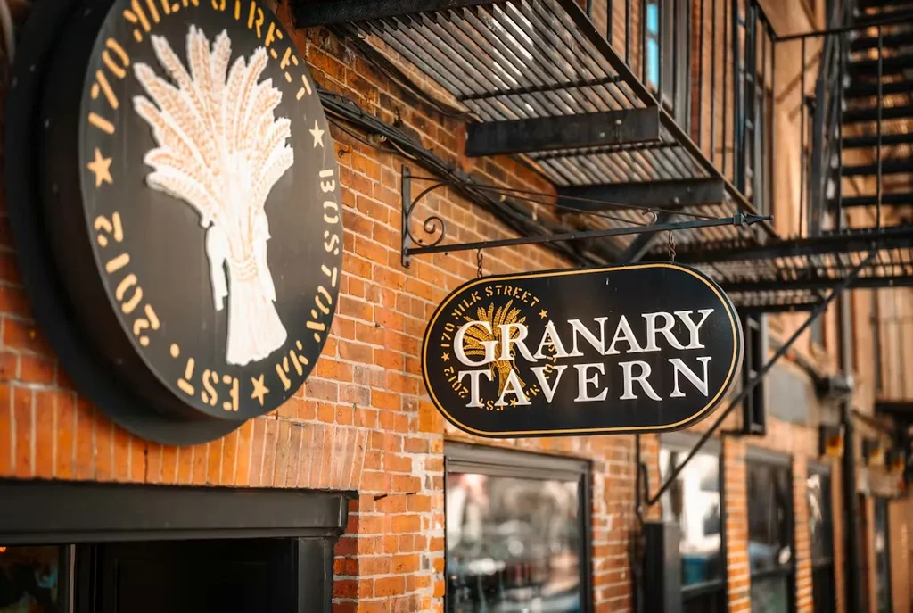 Two black Granary Tavern signs on a red brick building.