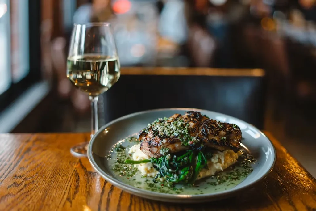Grilled meat with herb crust, potatoes, wine, served in a restaurant.