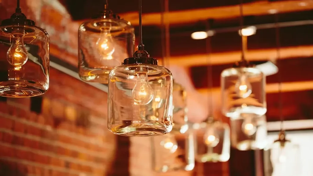 Hanging clear glass pendant lights with amber glow, brick wall.