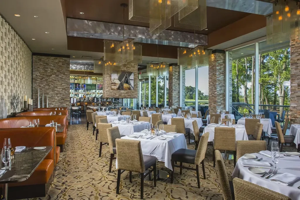 Elegant, empty restaurant with booths, bar, and golf course view.