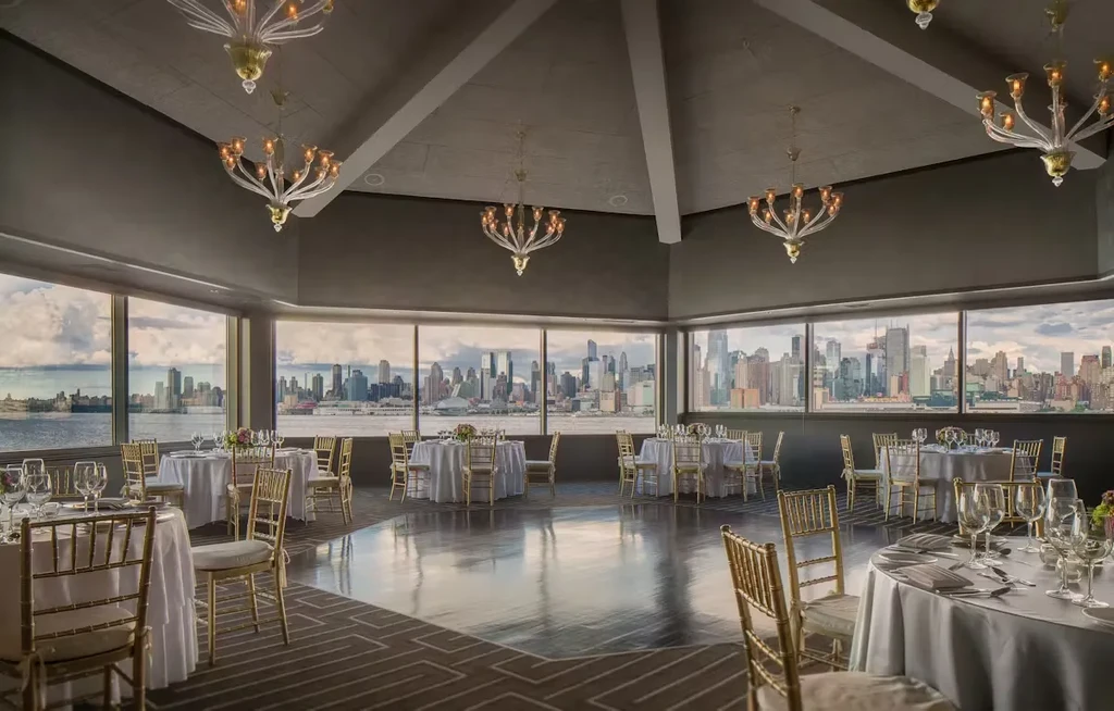 Elegant event venue with set tables, chandeliers, and city skyline view.