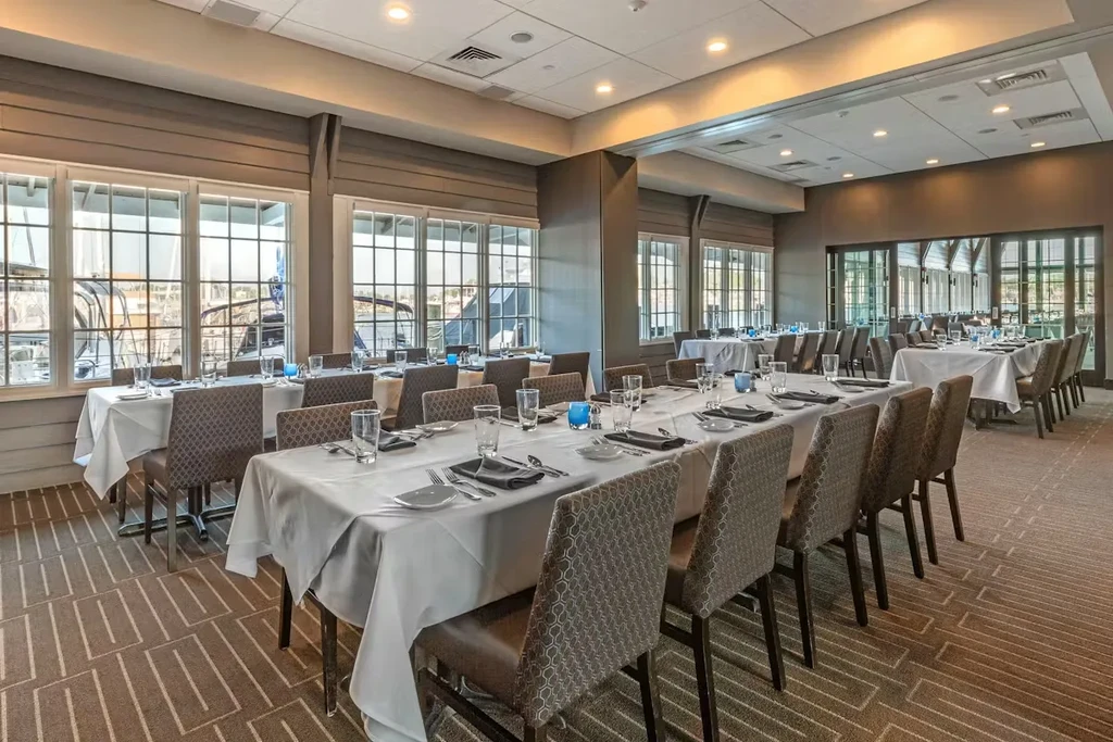 Empty elegant dining room with set tables and marina view.