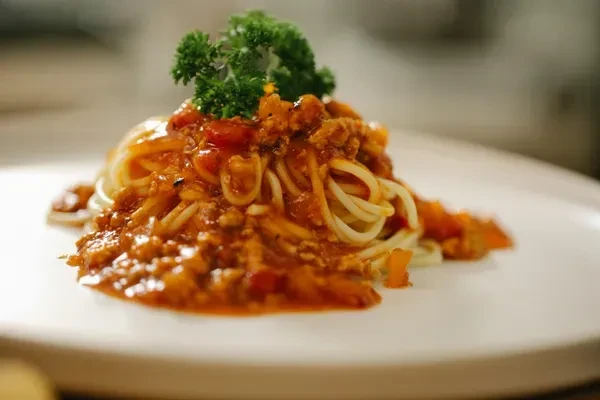 A plate of spaghetti bolognese with meat sauce and parsley.
