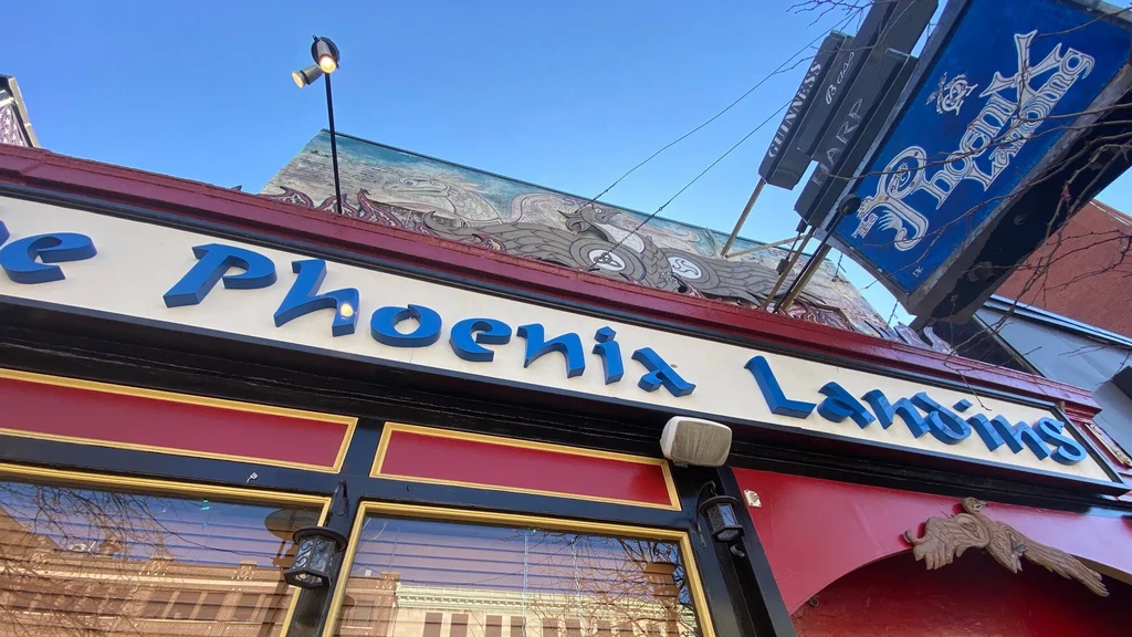 Exterior of The Phoenix Landins pub with Celtic frieze and Guinness sign.