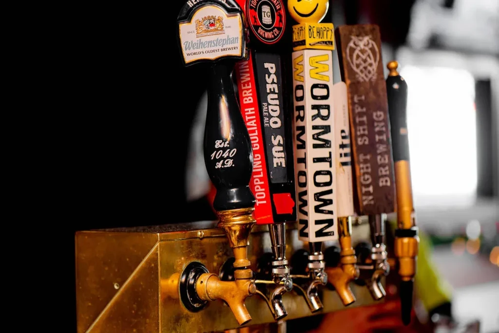 Close-up of several branded beer tap handles on a brass draft system.
