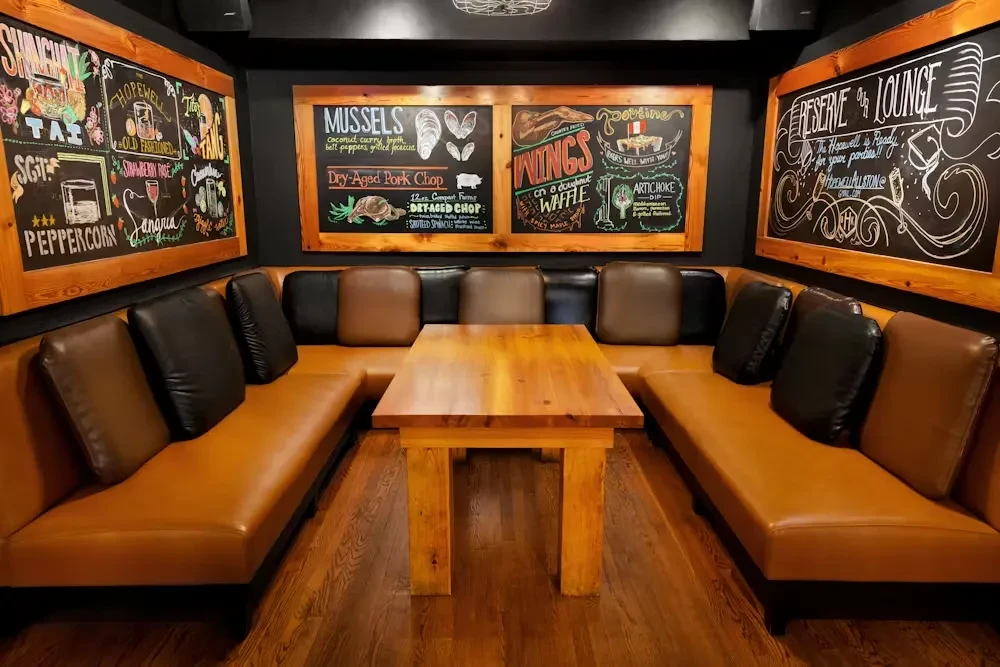 U-shaped booth and three menu chalkboards on dark walls.