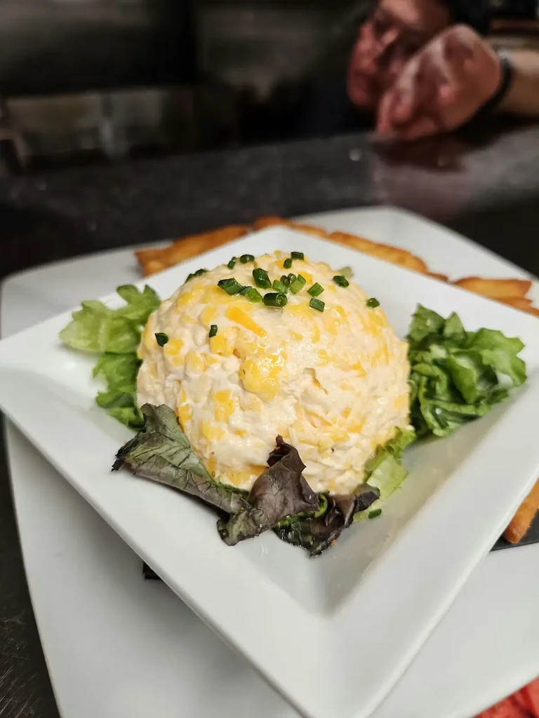 Creamy yellow salad with chives and lettuce on a white plate.