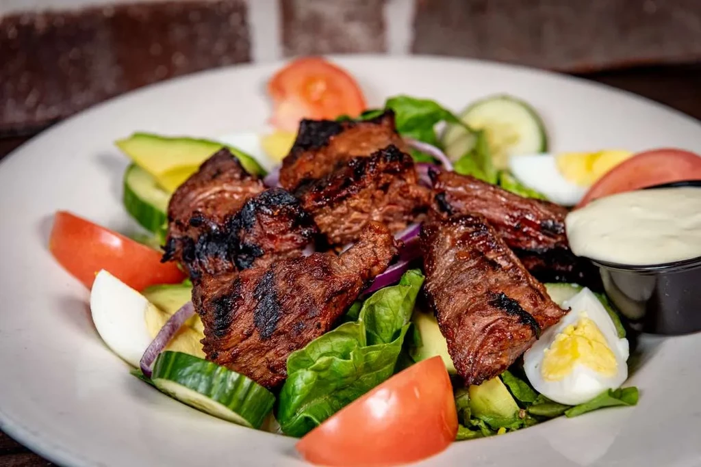 Steak salad with grilled steak, lettuce, tomatoes, eggs, avocado.