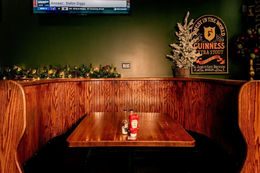 Holiday-decorated pub booth with sports on TV and a Guinness sign.