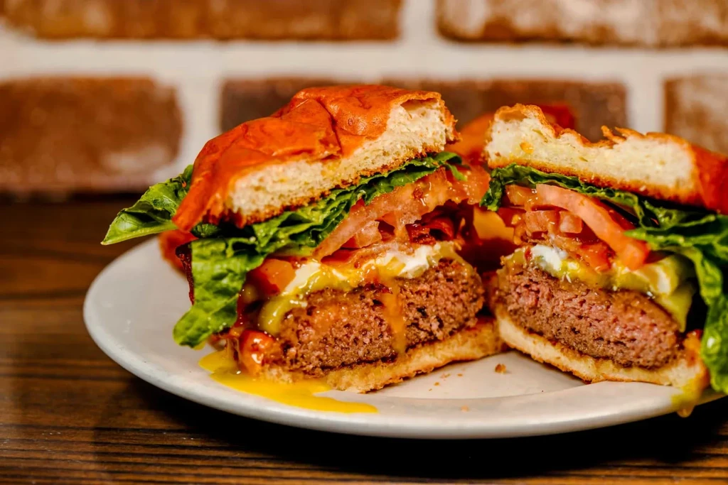 Halved burger on a plate, showing patty, egg, lettuce, and tomato.