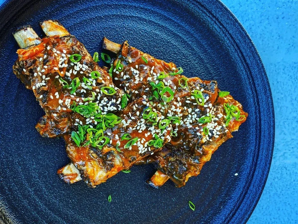 Dark, glossy glazed ribs with sesame seeds and green onions.