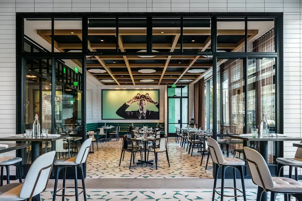 Empty modern restaurant with geometric floor, subway tiles, and wall art.