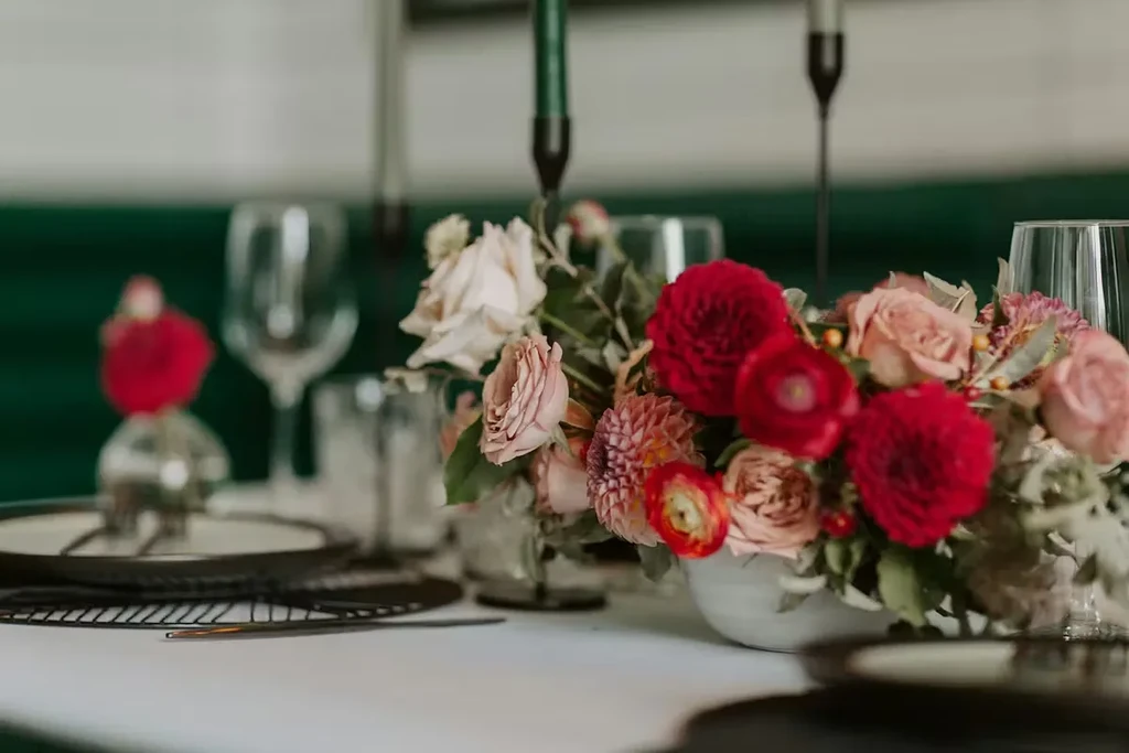 Lush red, pink, and cream floral centerpiece on a dining table.