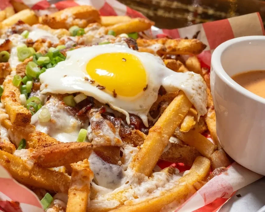 Loaded fries with melted cheese, meat, green onions, and a fried egg.