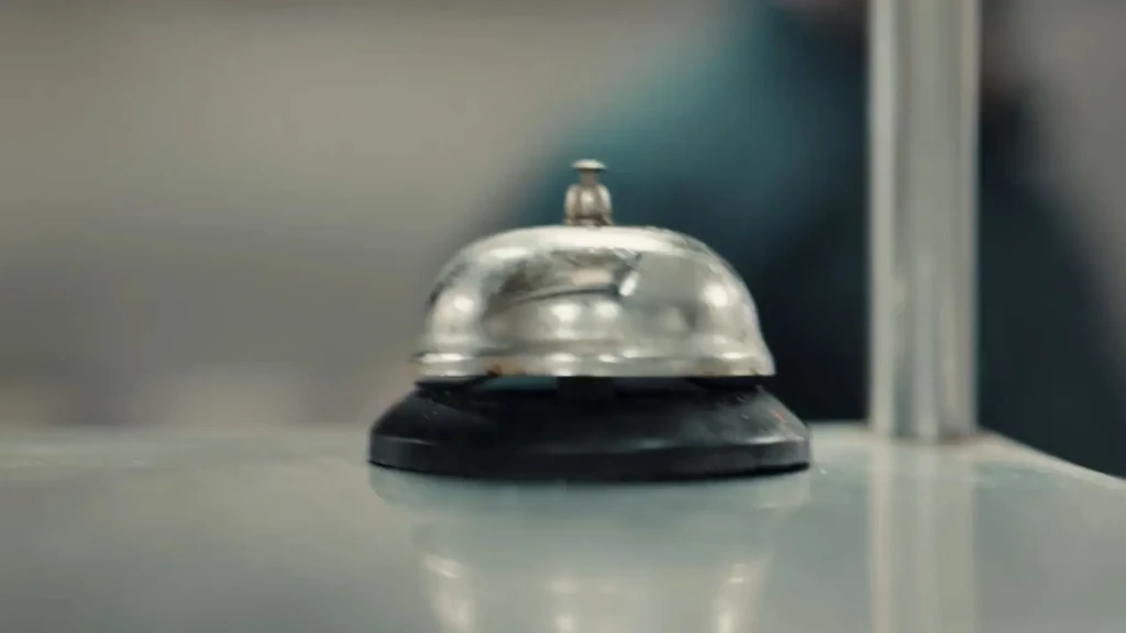 Worn silver service bell with a black base on a light counter.