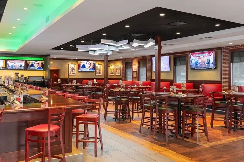 Empty sports bar and restaurant with a bar, TVs, and dining tables.