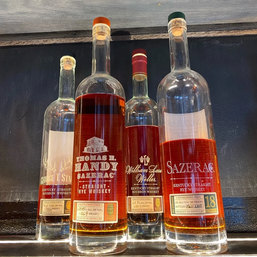 Four labeled bourbon and rye whiskey bottles with corks and seals.