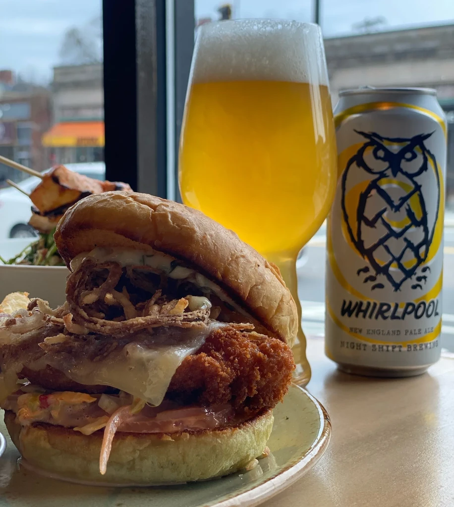 Crispy fried chicken sandwich, beer glass, and Night Shift beer can.