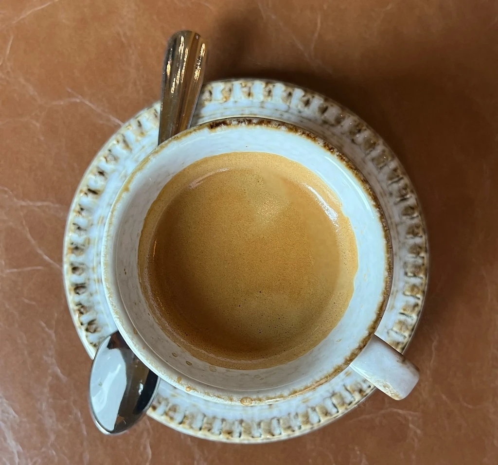 Espresso with golden-brown crema in a rustic ceramic cup and saucer.