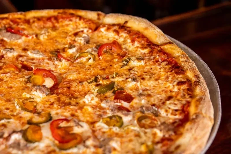 Close-up of a freshly baked pizza with cheese, peppers, and sausage.