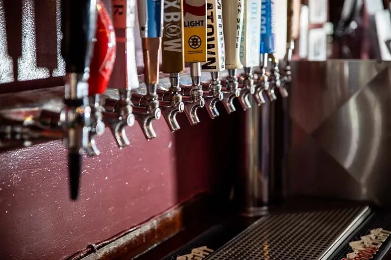 Row of branded chrome beer taps above a dark bar counter.