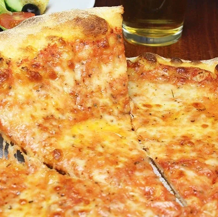 Freshly baked cheese pizza with stretched, melted mozzarella, salad, and beer.