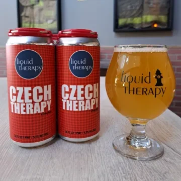 Two 'Liquid Therapy' checkered beer cans and a branded glass of beer.