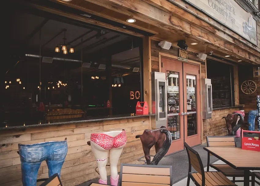 Rustic 'Restaurant & Country Bar' with wooden facade and whimsical leg planters.