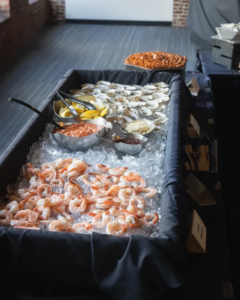 Buffet display of shrimp, local oysters on ice, and cocktail sauce.