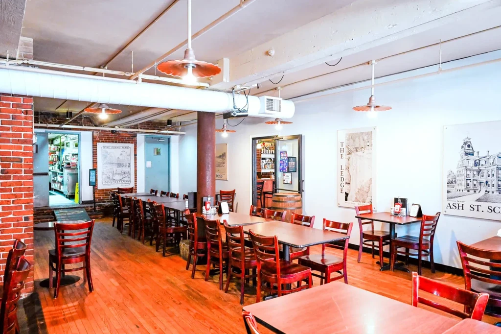 Empty restaurant, well-lit, with exposed brick, wooden tables, industrial elements.