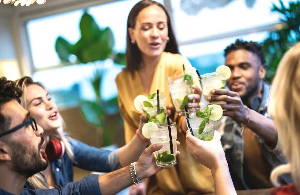 Diverse young adults toast with mojito-style cocktails.