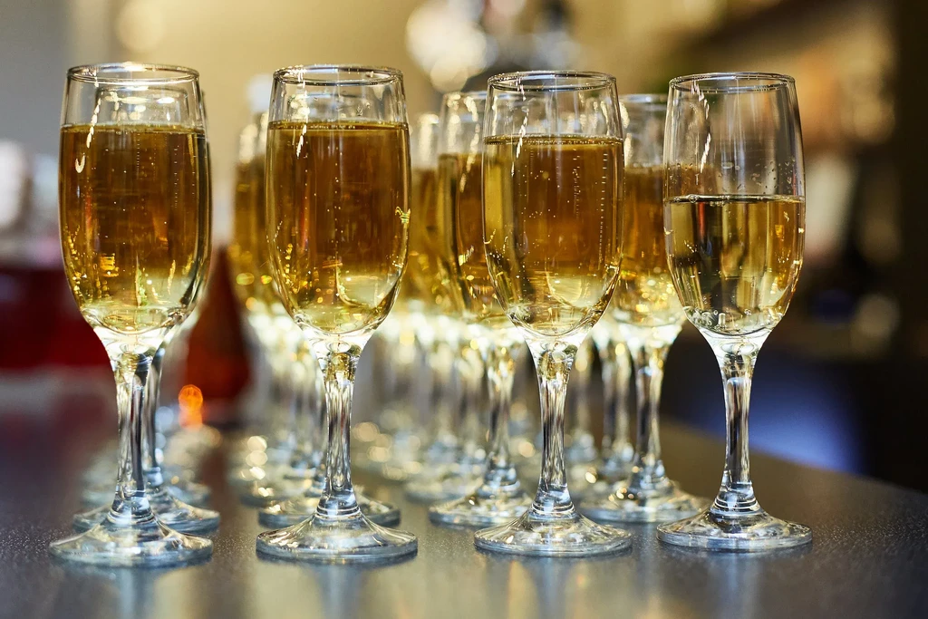 Rows of effervescent champagne flutes on a dark, reflective surface.