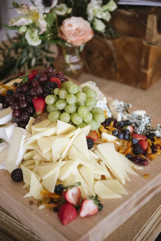 Colorful charcuterie board with cheeses, grapes, berries, and dried fruit.