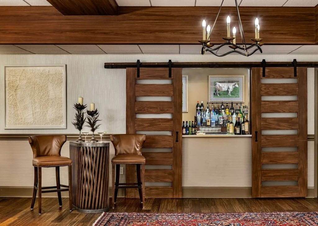 Modern bar interior with open barn doors, stocked bar, and stylish seating.