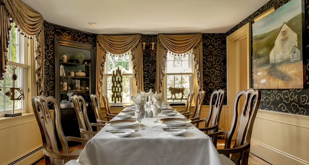 Formal dining room with elegant long table, ornate chairs, and rich decor.