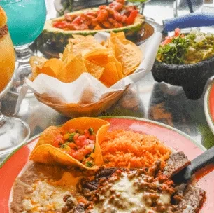 Close-up of a dining table with various Mexican dishes and colorful drinks.