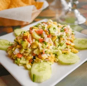 Diced avocado, tomato, onion salad with cucumber and tortilla chips.