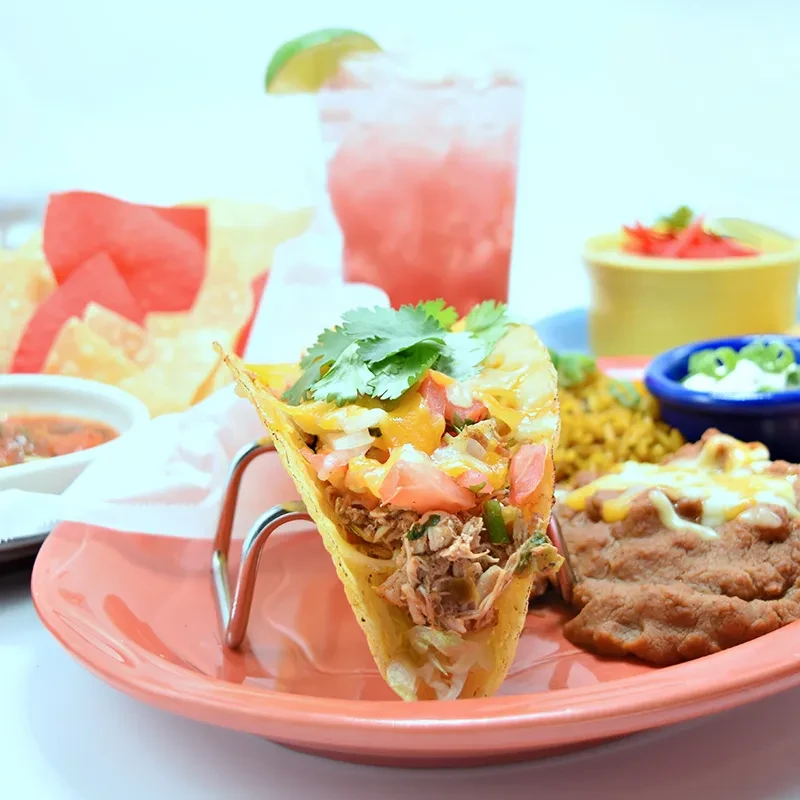 Mexican hard-shell taco, beans, rice, chips, salsa, and pink drink.